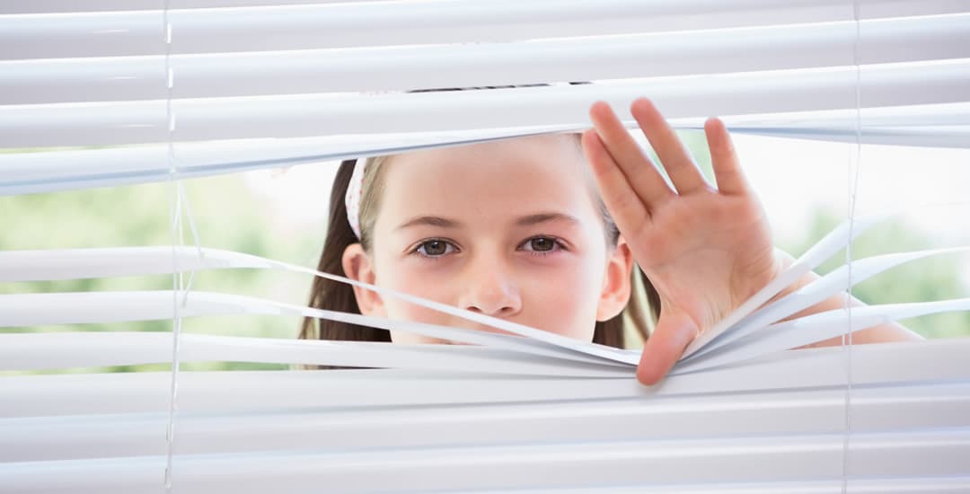 Child peeking through venetian blinds