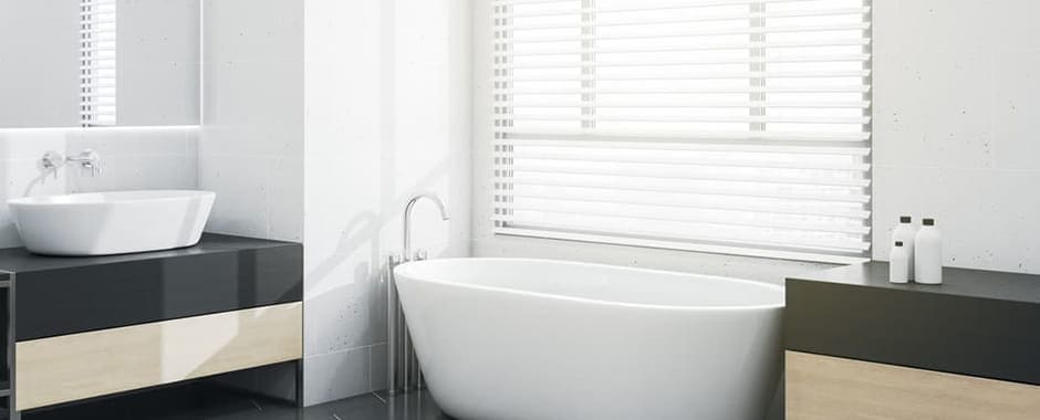 White faux wood blinds in bathroom above bathtub