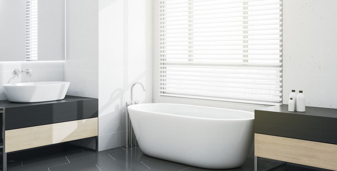 White faux wood blinds in bathroom above bathtub