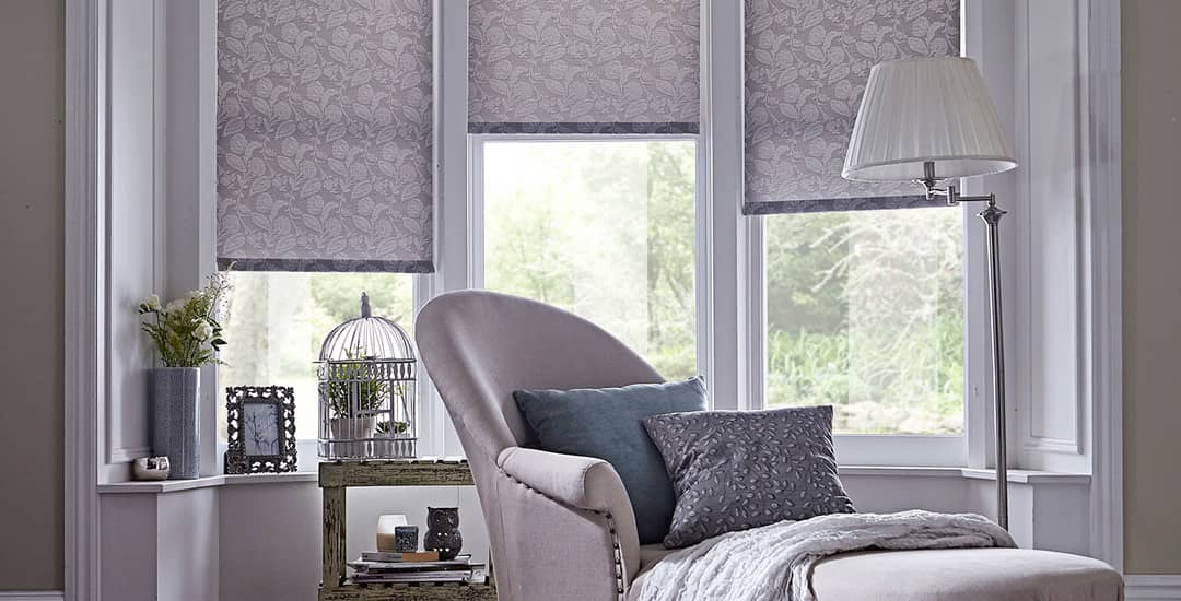 Grey patterned roller blinds in living room bay window 