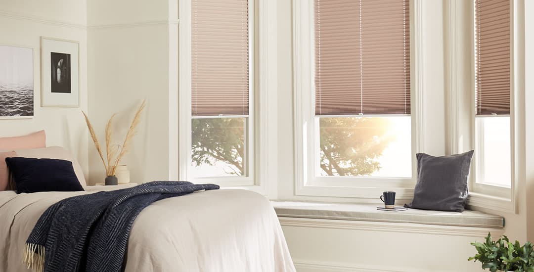 Peach pleated blinds in bedroom bay window
