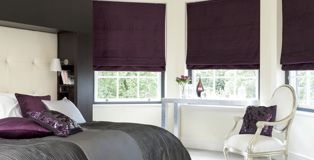 Purple roman blinds in bedroom bay window