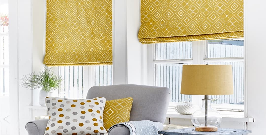 Yellow patterned roman blinds inside window recess