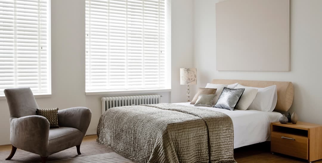 White faux wood blinds with tapes in bedroom