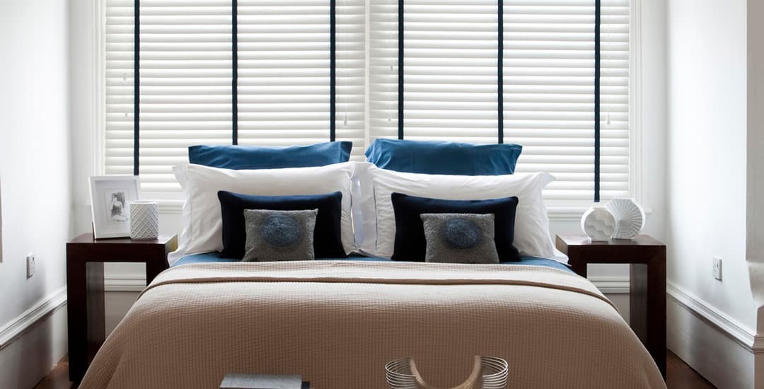 White wooden blinds with black tapes in bedroom