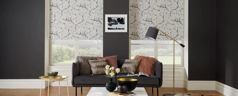 Light grey floral roller blinds in lounge with dark walls
