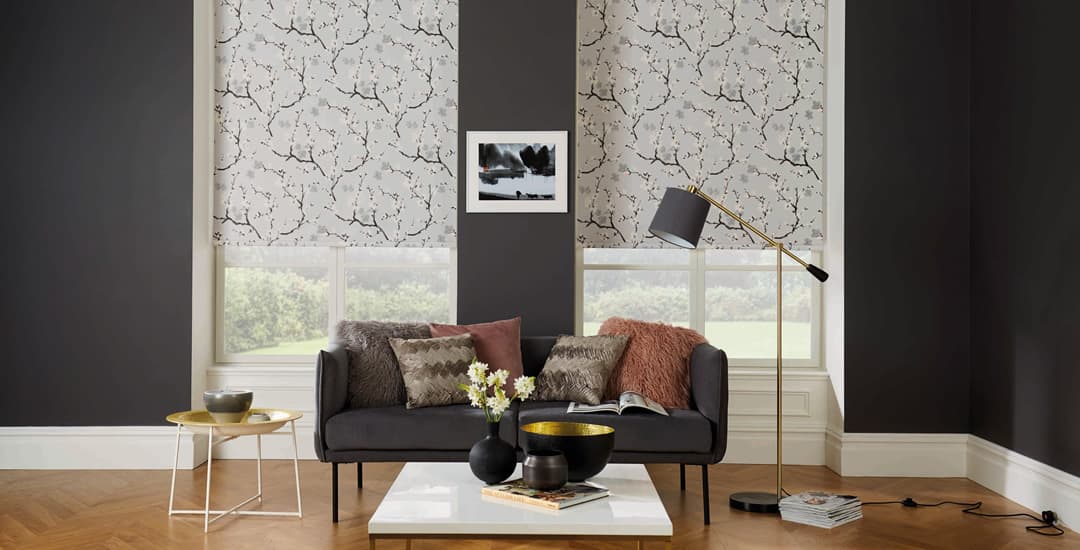 Light grey floral roller blinds in lounge with dark walls
