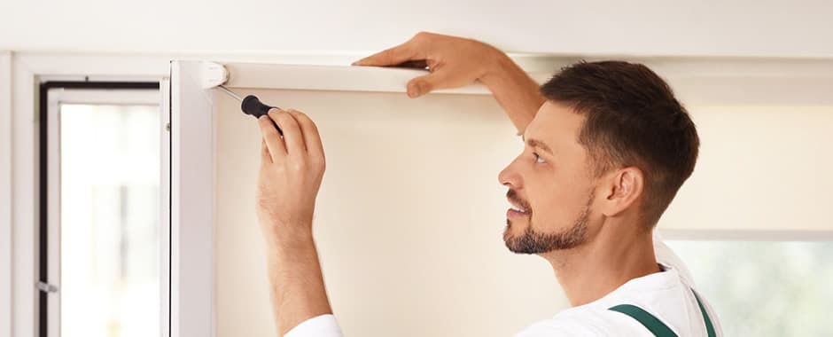 Man with screwdriver undertaking roller blind maintenance