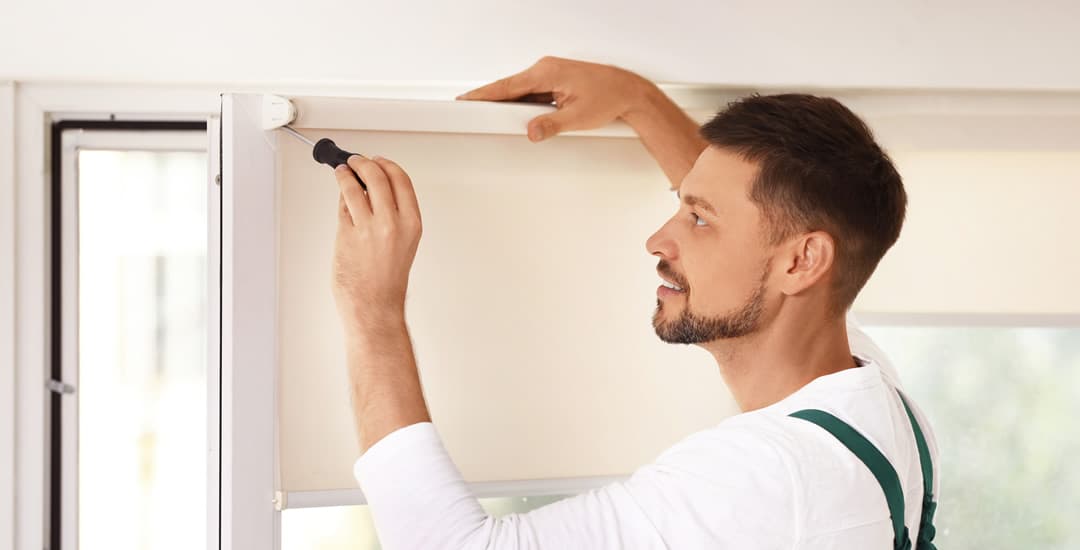 Man with screwdriver undertaking roller blind maintenance