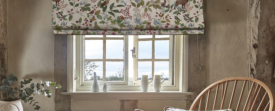 Floral patterned thermal roman blinds in cosy county cottage
