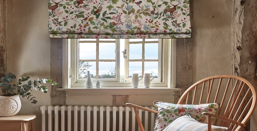 Floral patterned thermal roman blinds in cosy county cottage