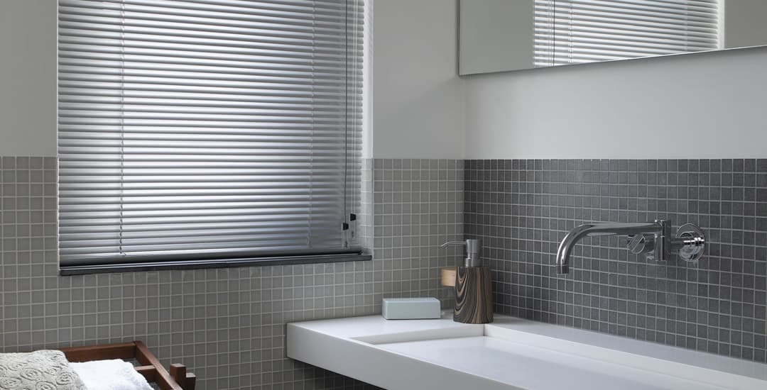 Silver aluminium venetian blind in small grey bathroom