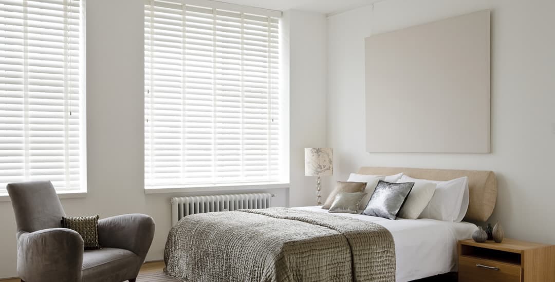 White wooden venetian blinds with tapes in bedroom