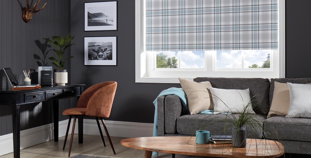 Blue tartan blackout roller blinds in living room with laptop