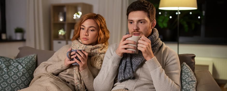 Couple trying to keep warm in cold living room