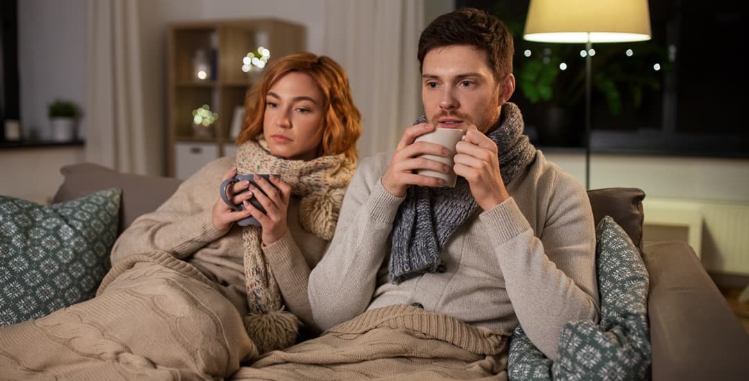 Couple trying to keep warm in cold living room