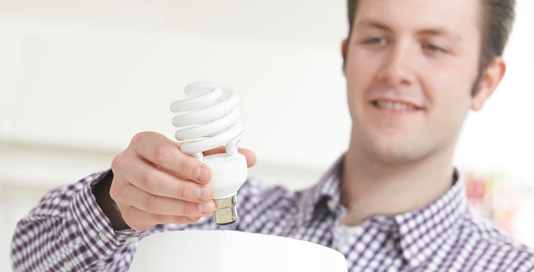 Man putting low energy lightbulb into lamp at home
