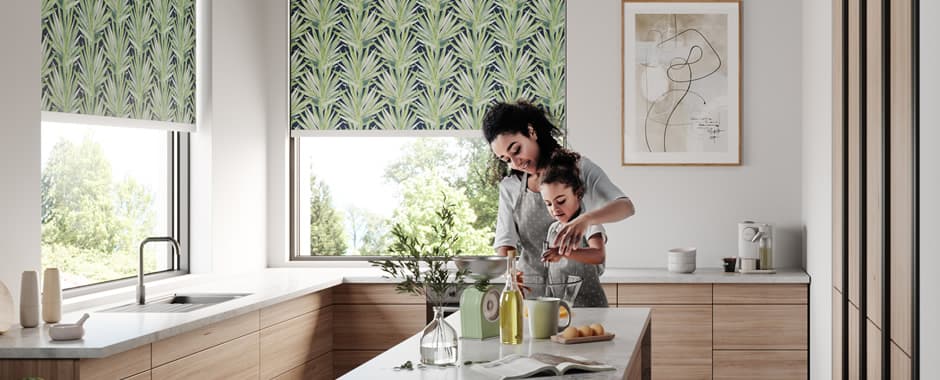 Mother and child in kitchen with tropical leaves patterned roller blinds