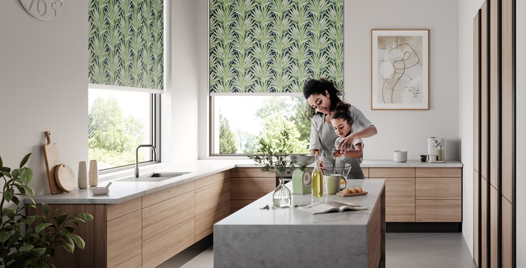 Mother and child in kitchen with tropical leaves patterned roller blinds