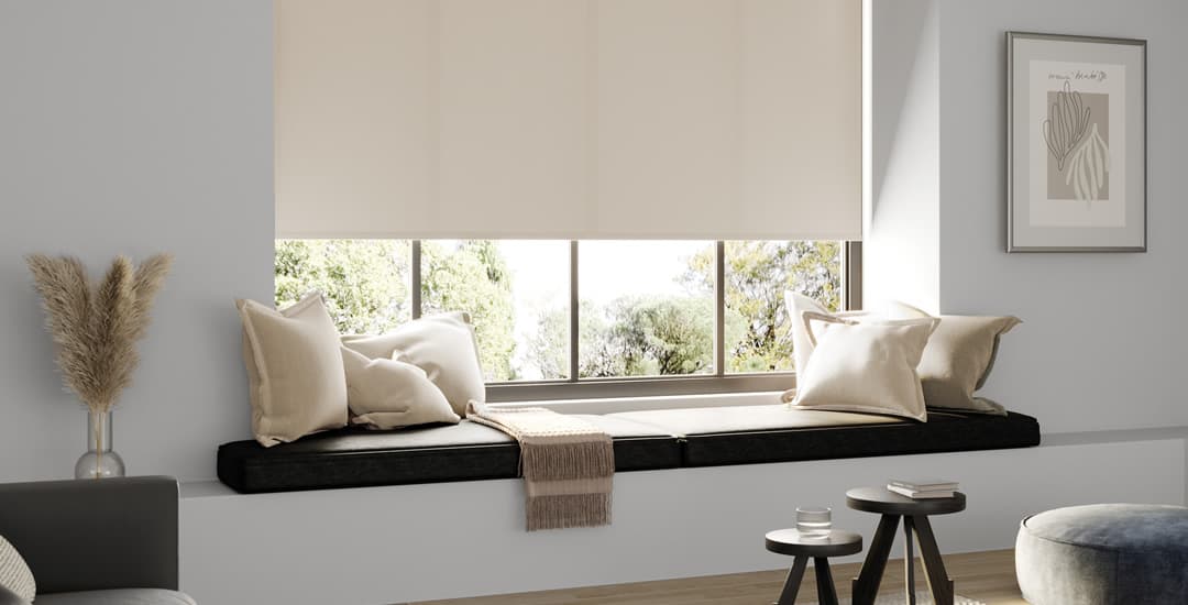 Beige roller blinds in grey room with window seat