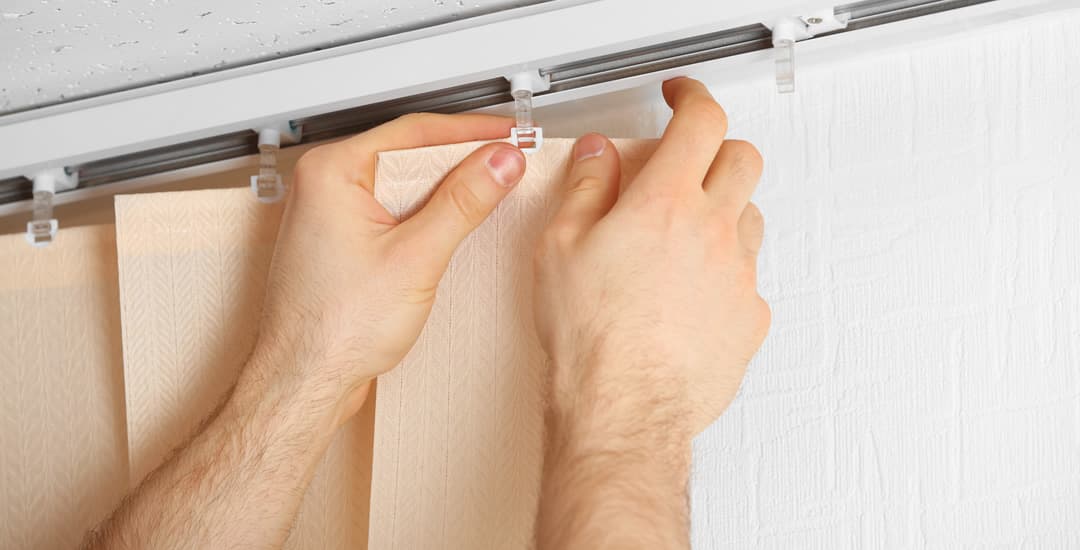 Man’s hands fitting vertical blinds