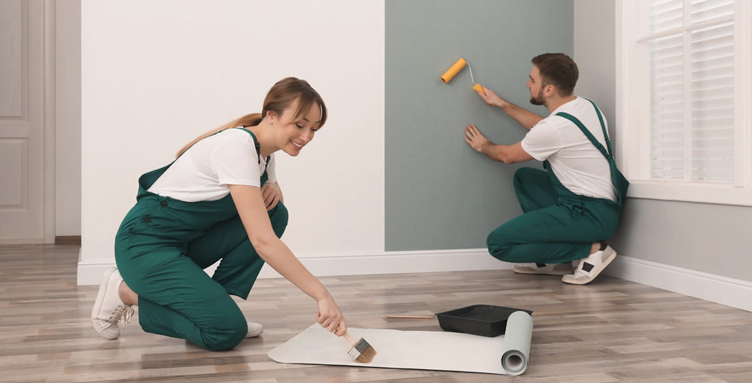 Couple wallpapering a wall