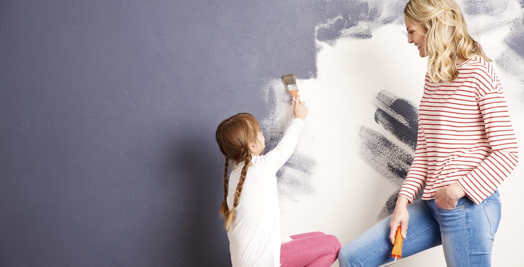 Mother and daughter painting a wall