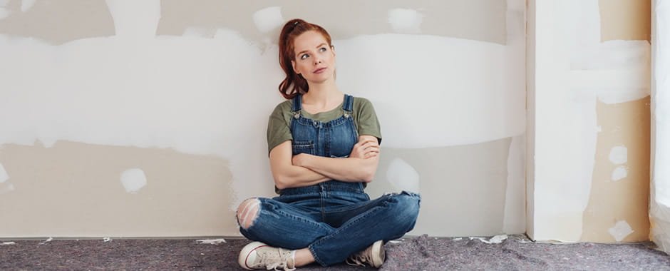 Woman sat in front of unpainted wall thinking