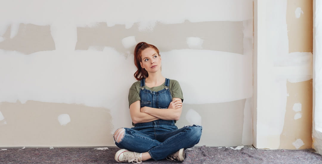 Woman sat in front of unpainted wall thinking