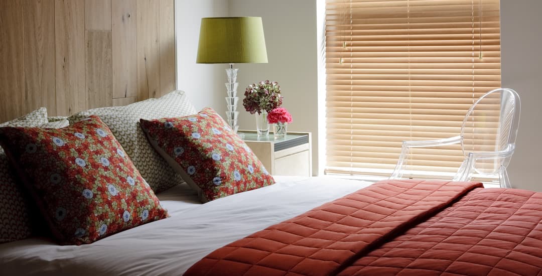 Honey real wood blinds in red themed bedroom