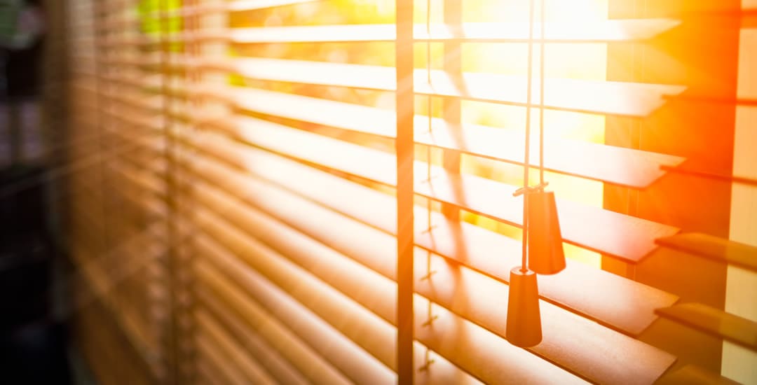 Wooden blinds with the summer sun streaming through the window