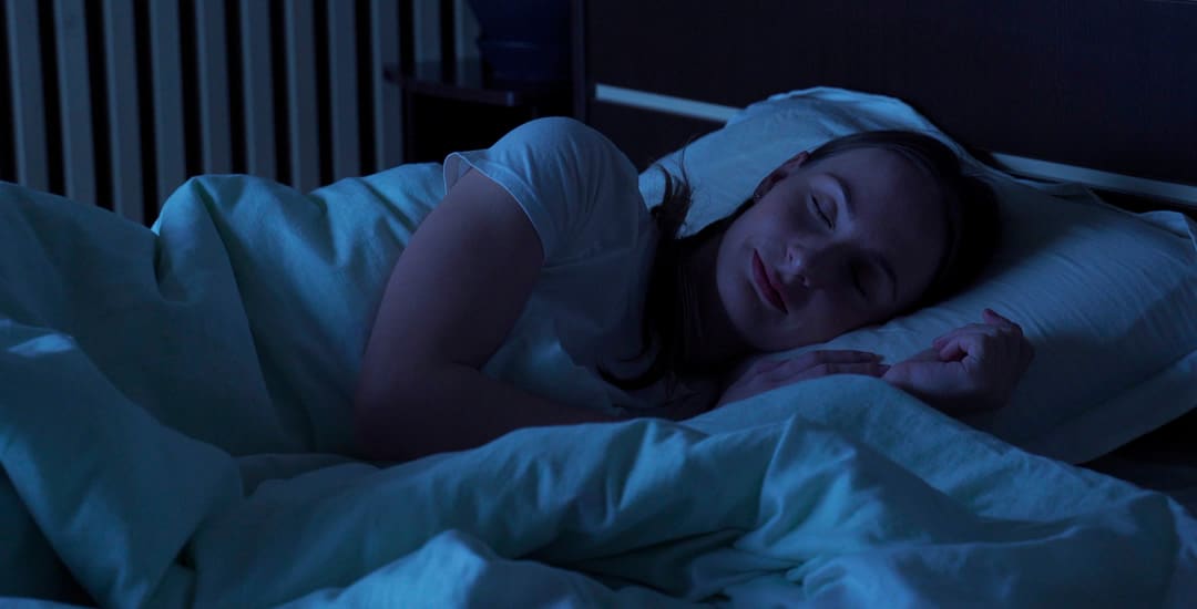 Young woman sleeping in dark bedroom