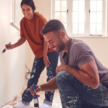 Couple painting wall with carpet covered