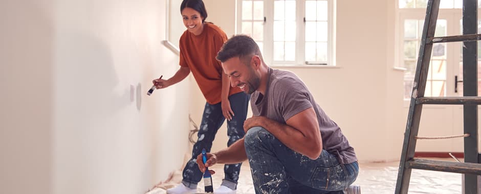 Couple painting wall with carpet covered