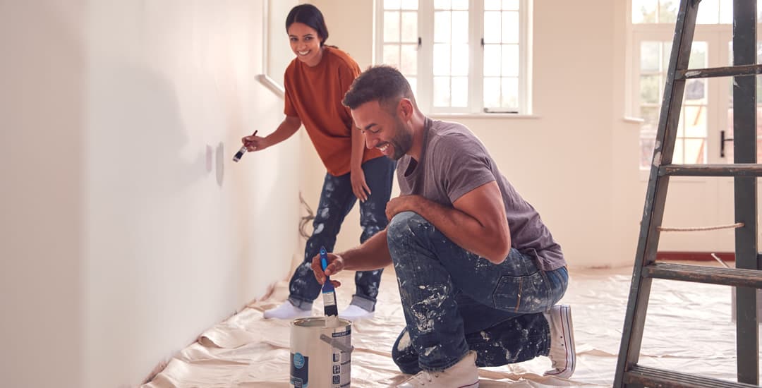 Couple painting wall with carpet covered