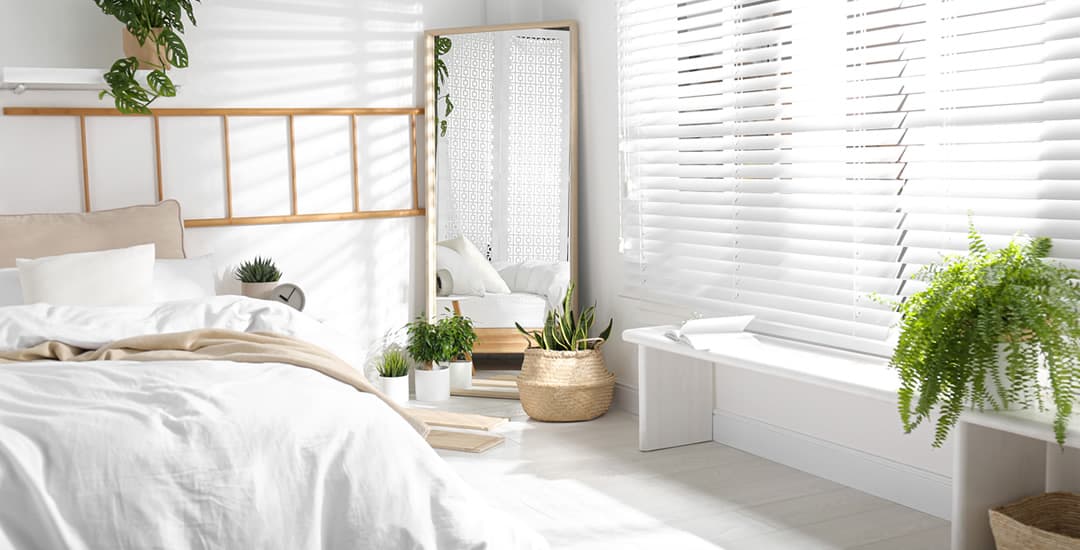 Large white faux wood blinds in bedroom