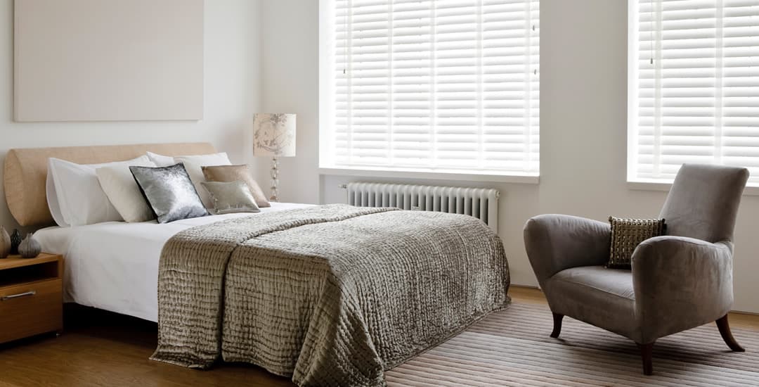 White faux wood blinds with tapes in bedroom