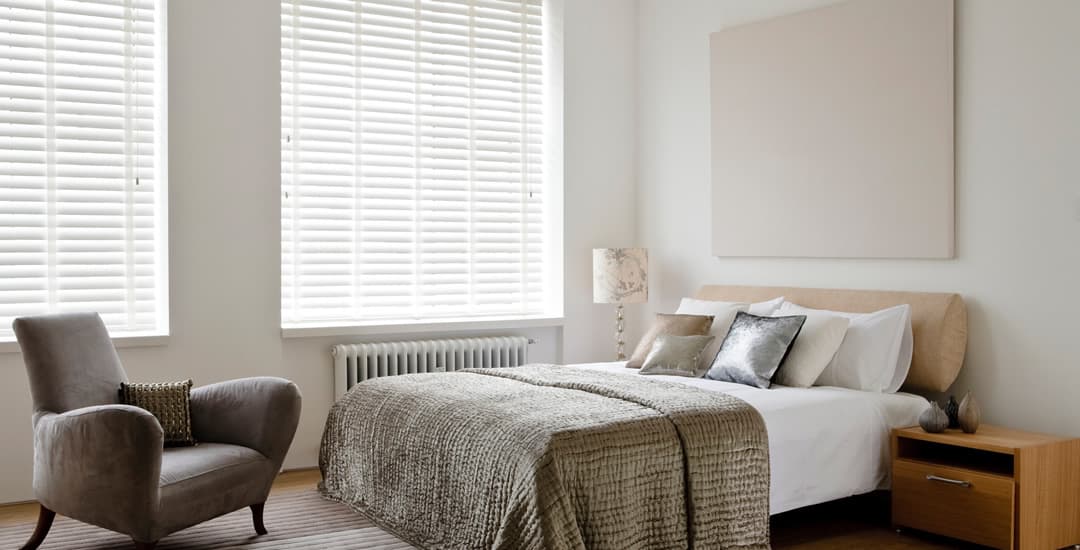 White faux wood venetian blinds with tapes in large bedroom
