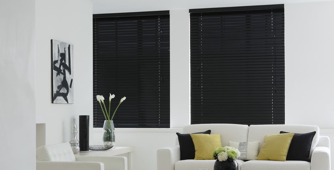 Closed black wooden blinds during daytime in living room