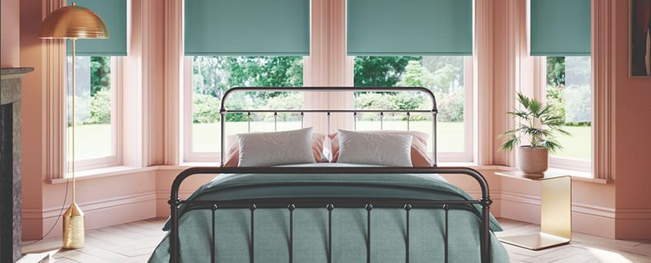 Green blackout roller blinds in a luxurious bedroom bay window