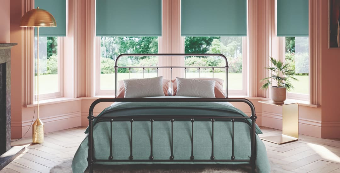 Green blackout roller blinds in a luxurious bedroom bay window