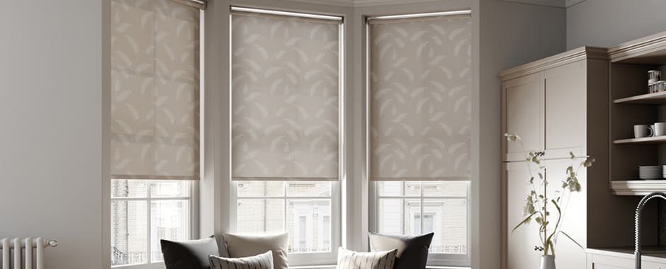 Beige leaf patterned roller blinds in kitchen bay window
