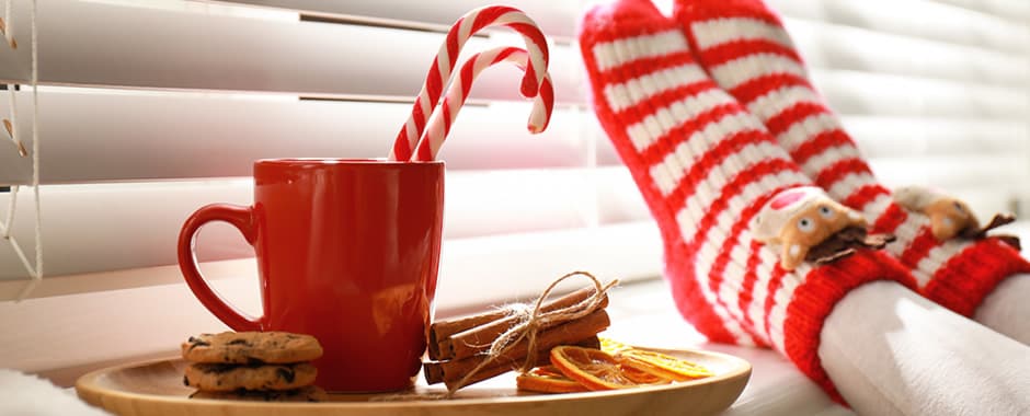 Christmas cookies, drink and socks in front of white wooden blinds