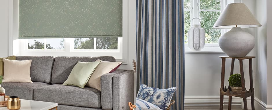 Green blackout roller blinds next to beige and blue blackout curtains
