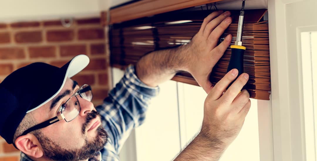 Man installing wooden blind