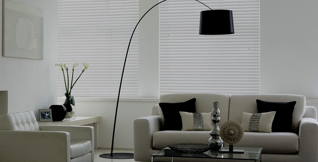 White faux wood blinds in living room in the evening
