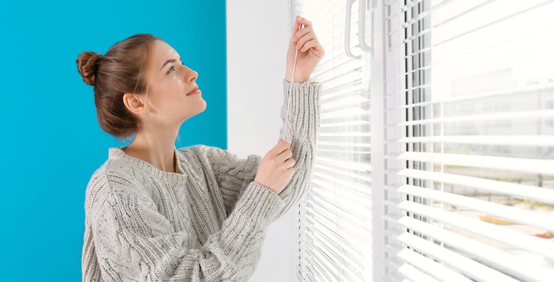 Woman operating window blinds