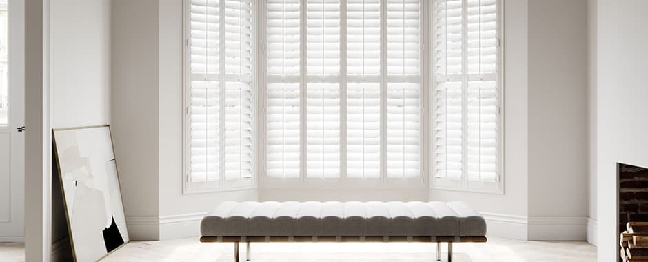 White plantation shutters in minimalist living room bay window