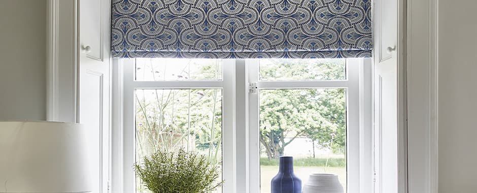 Blue and grey geometric patterned roman blinds in a cottage window