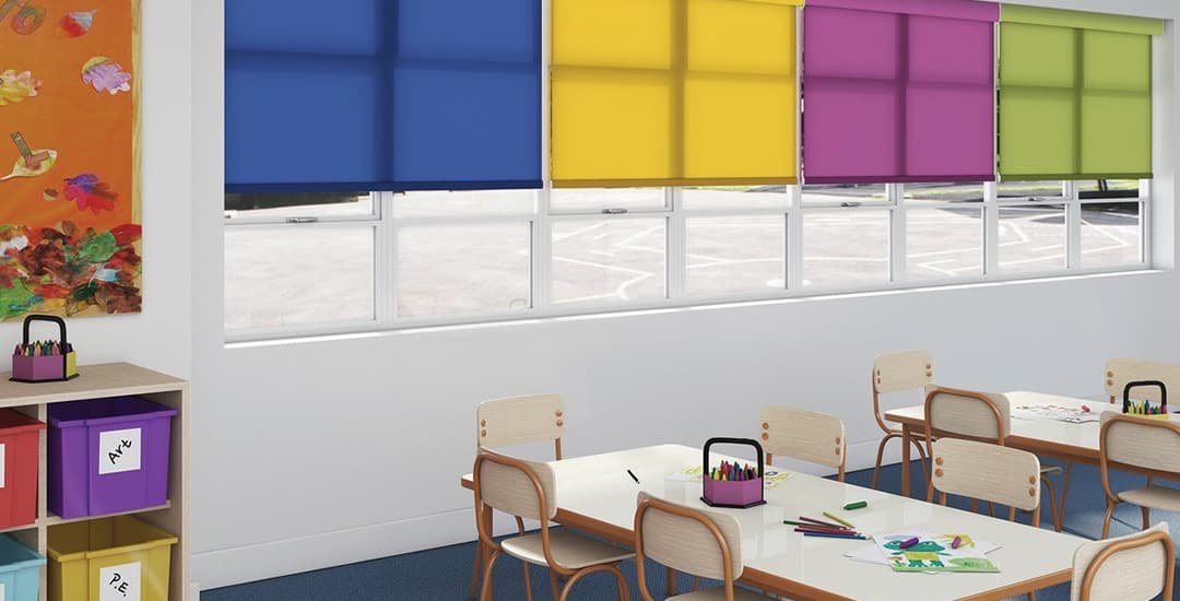 Colourful commercial dim out roller blinds in school classroom